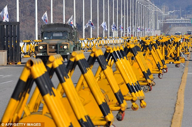 Threat level raised: A South Korean military vehicle drives past barricades on the road leading to North Korea, which is expecting to launch a missile 'at any time'