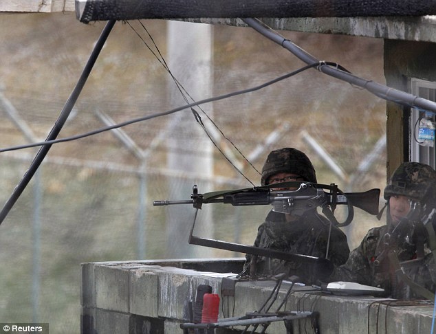 Weapons ar the ready: South Korean soldiers stand guard at an observation post near the demilitarised zone which separates the two Koreas in Paju, north of Seoul