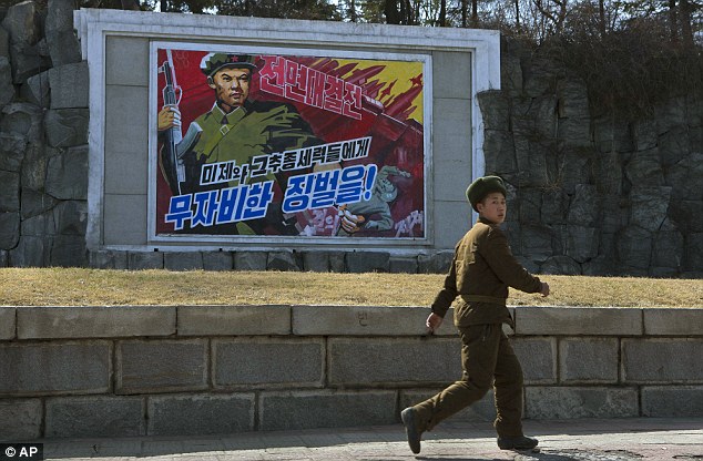 A North Korean soldier passes by roadside propaganda depicting a North Korean soldier killing a U.S. soldier in Pyongyang, North Korea today. The poster reads in Korean 