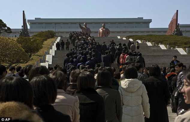 Young North Korean workers and students climb stairs to the base of bronze statues of the late leaders Kim Il Sung and Kim Jong Il during an event to pledge loyalty to the country in Pyongyang