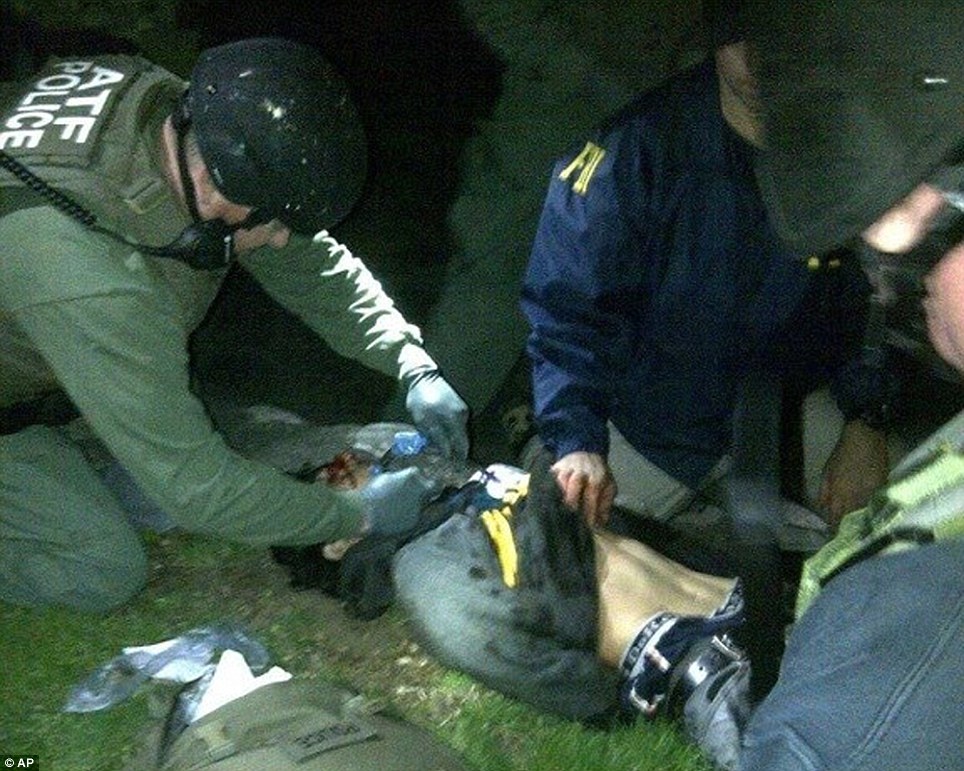 Wounded: Dzhokhar Tsarnaev, seen here moments after he was pulled from the boat where he was hiding, suffered a throat wound and a leg wound