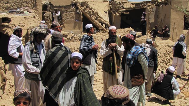 This file photo shows Afghan villagers standing at a house that was hit by a US-led NATO airstrike in Sajawand village in Logar Province, south of Kabul.