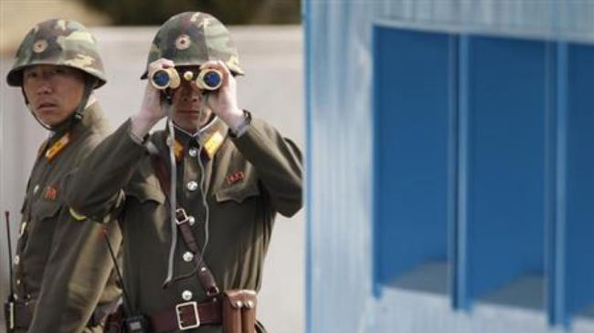 North Korean soldiers look to the South as they patrol at the truce village of Panmunjom in the demilitarized zone separating North Korea from South Korea, March 19, 2013.